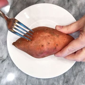 Piercing the sweet potato with a fork.