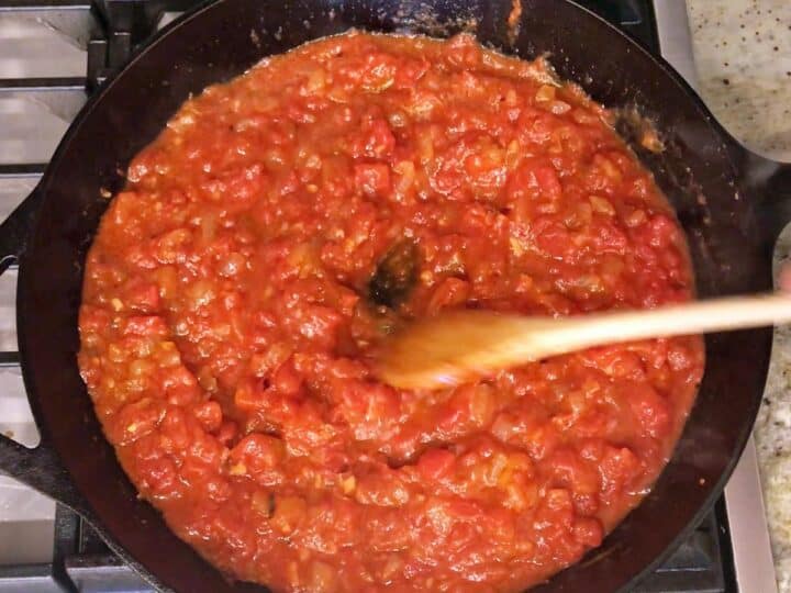 Adding tomatoes to the skillet.