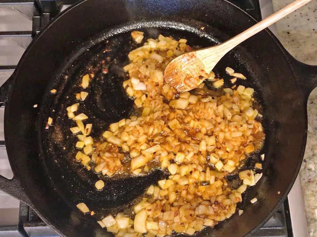 Adding spices to the onions in the skillet.