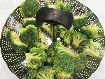 Raw broccoli in a steamer basket.