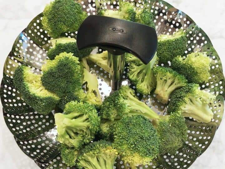 Raw broccoli in a steamer basket.