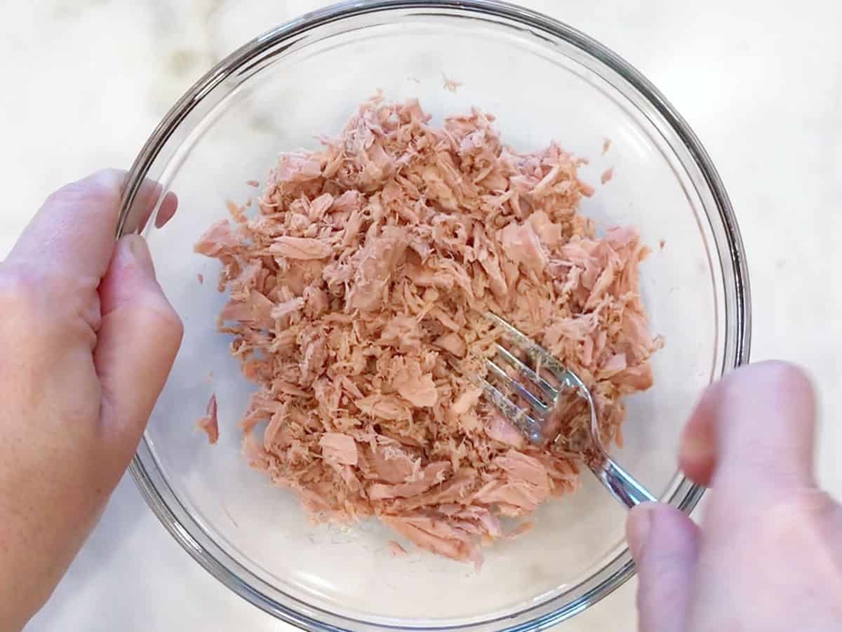 Flaking canned tuna with a fork.