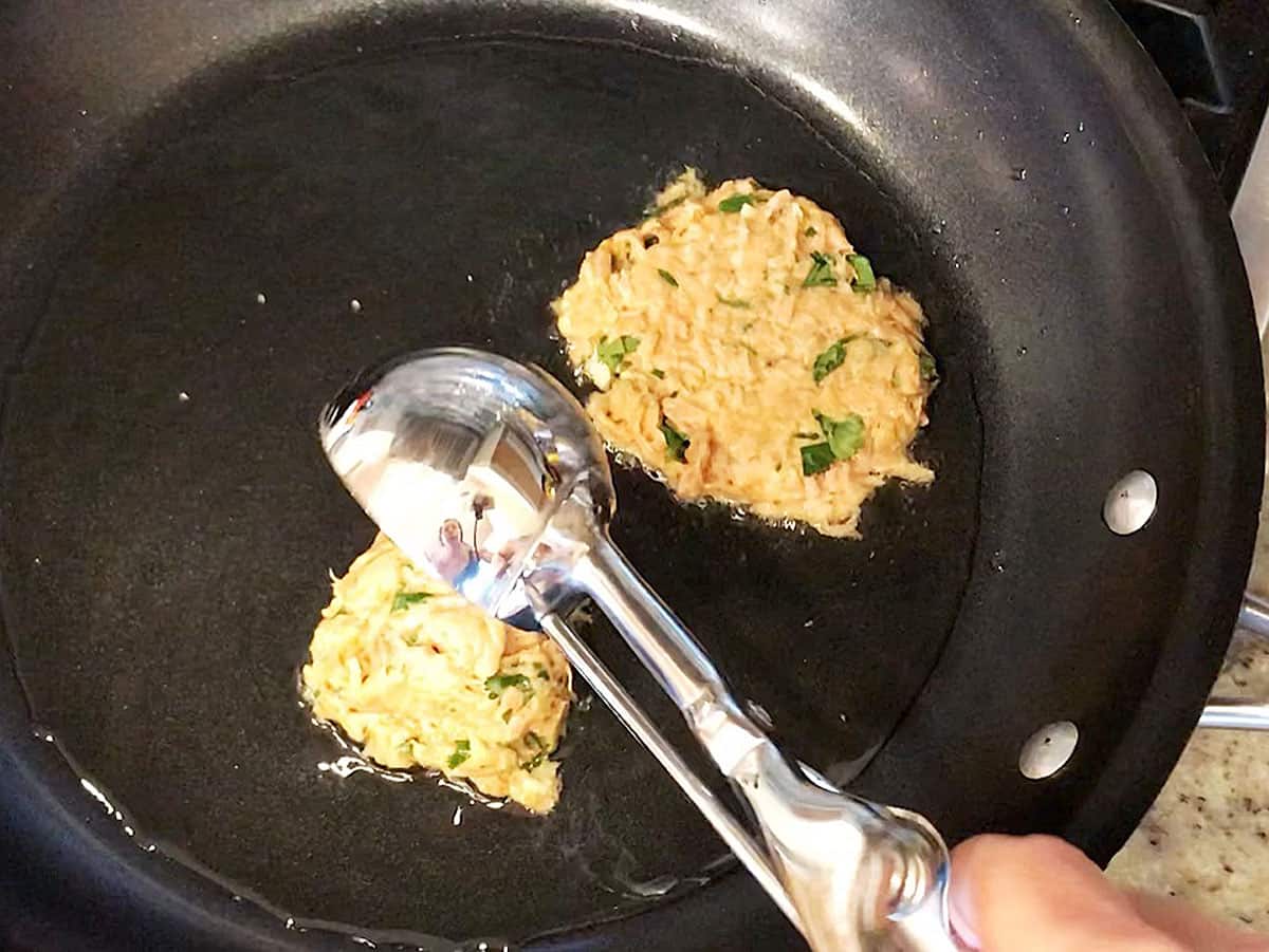 Scooping tuna patties into the skillet.