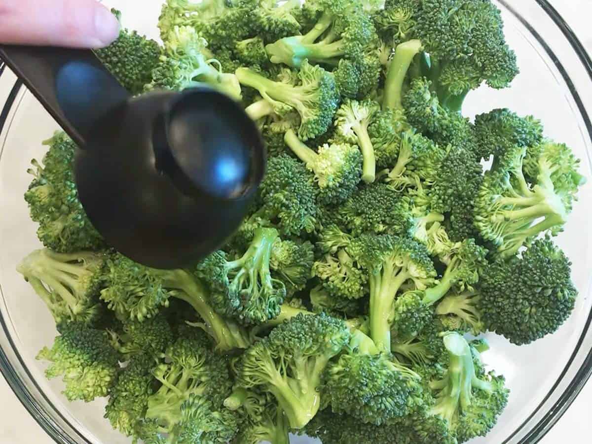 Adding water to the broccoli in the bowl.