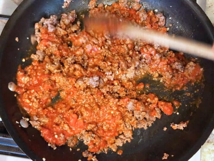 Adding marinara sauce to the ground beef.