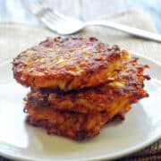 Three baked latkes are stacked on a white plate.