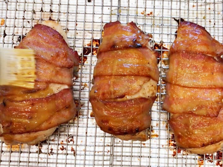 Brushing fully baked bacon-wrapped chicken breasts with more honey-mustard sauce.