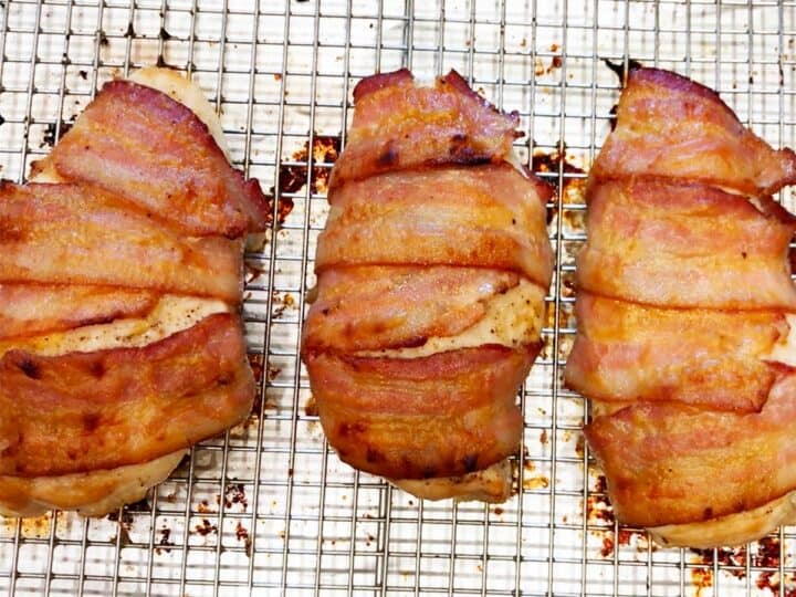 Bacon-wrapped chicken breast is shown fully baked in the baking sheet.