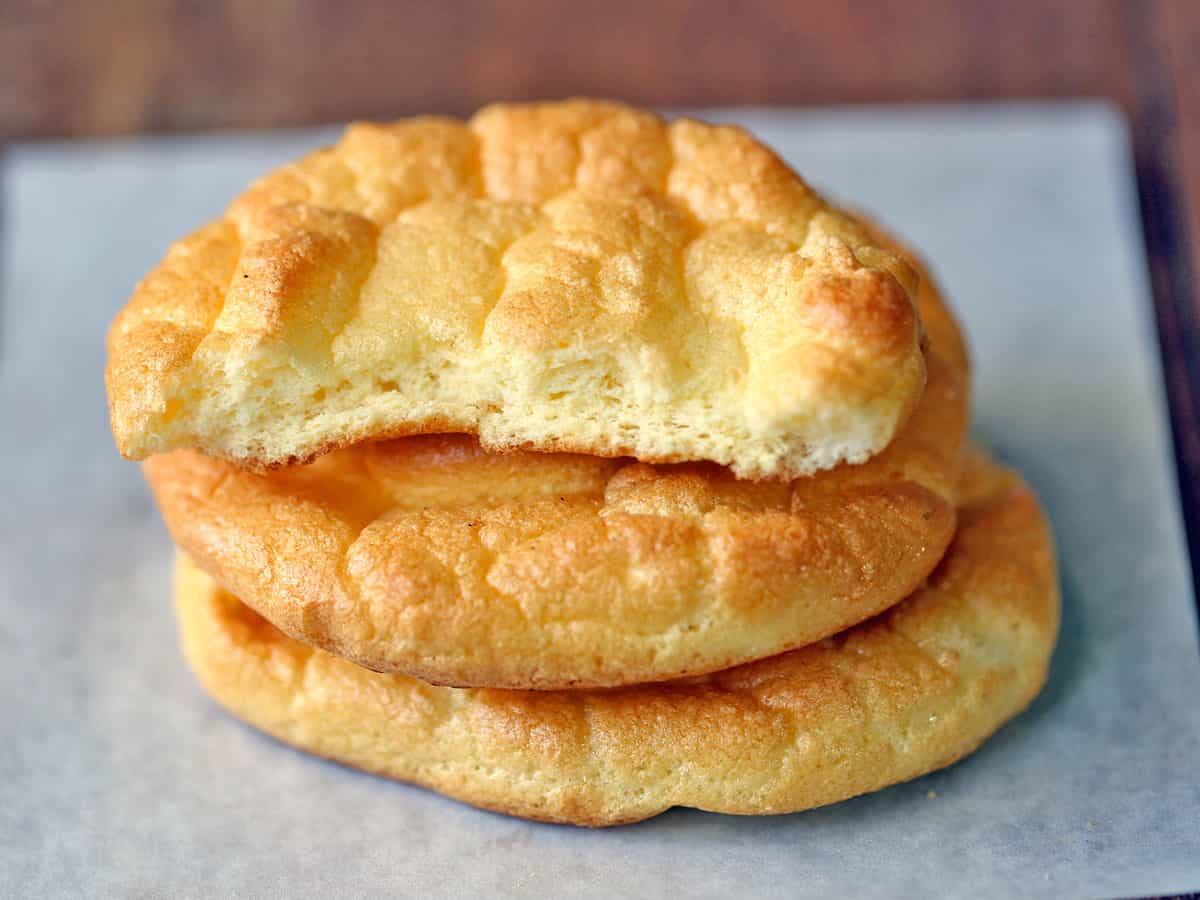 Three pieces of cloud bread, stacked. The top pieces is halved, showing the bread's spongy texture on the inside.