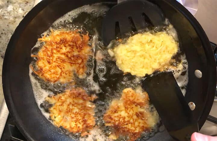 Flipping the latkes in the skillet.
