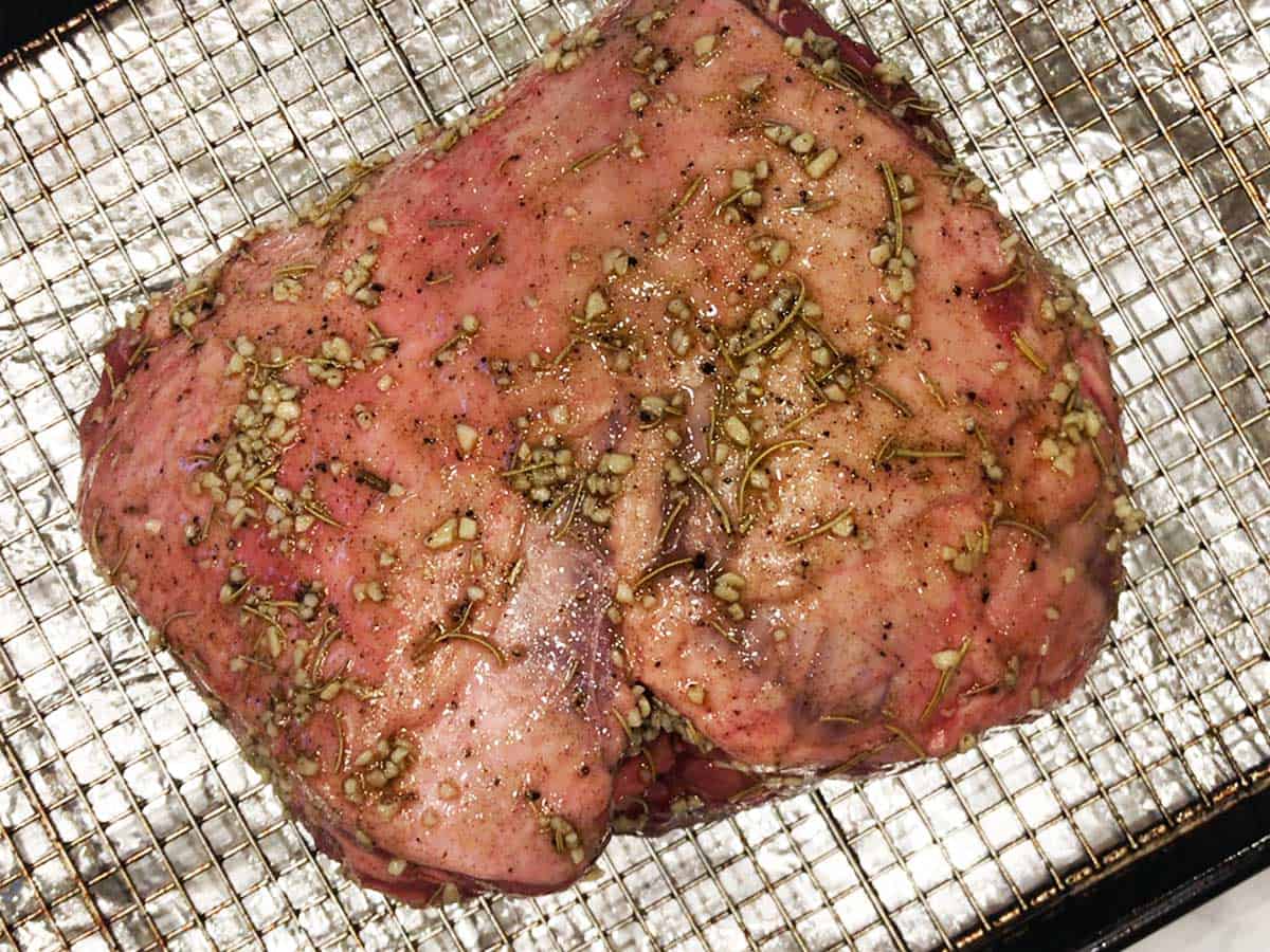 A coated leg of lamb is placed on a baking sheet.