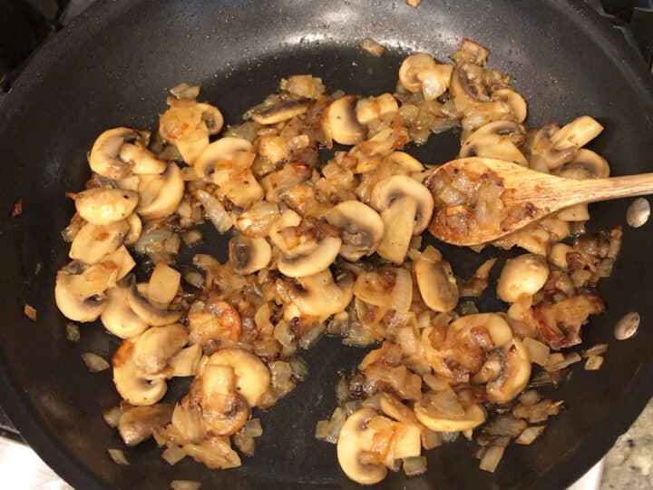 Cooked onions and mushrooms in a skillet.