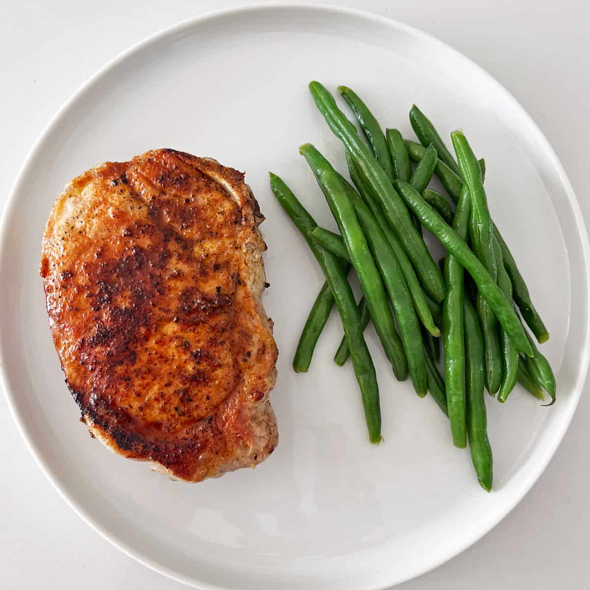 A pork chop served with green beans.