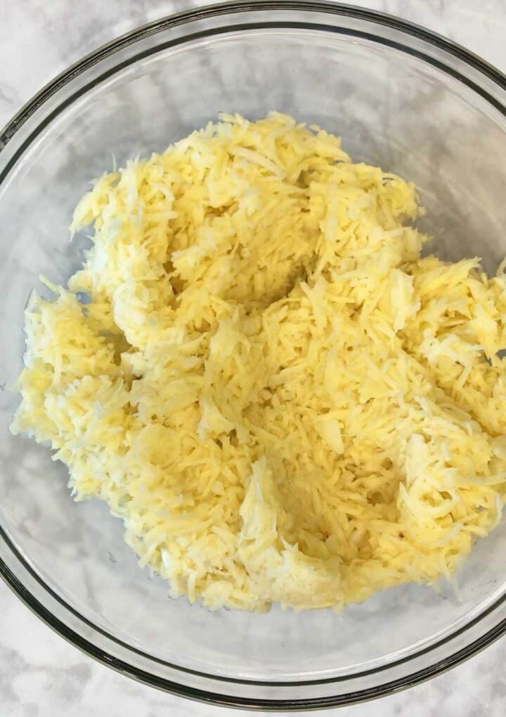 Shredded potatoes and onions in a bowl.