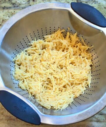 Shredded potatoes in a colander.