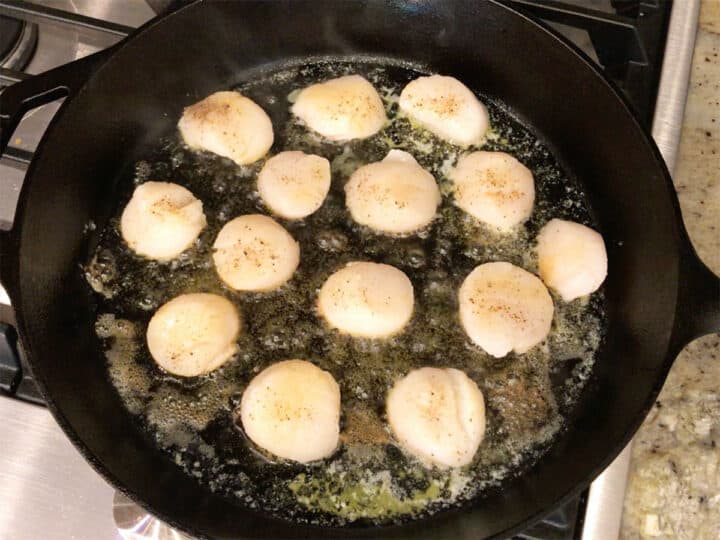 Searing the scallops on the first side.