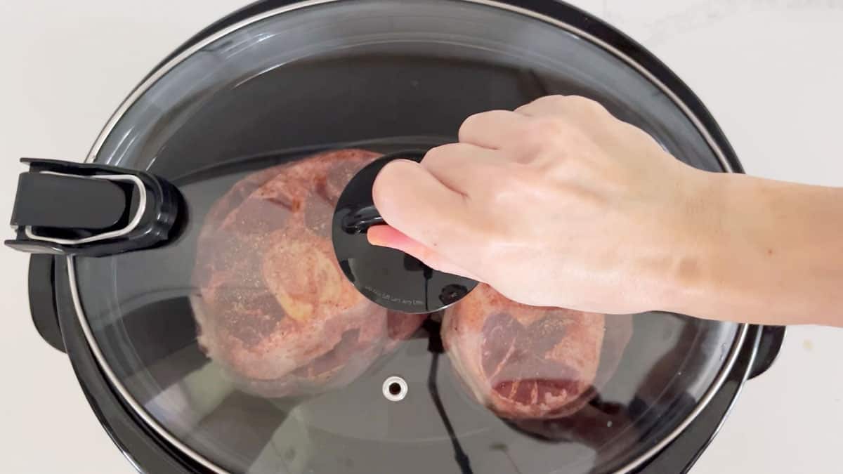 Covering the slow cooker with a lid.