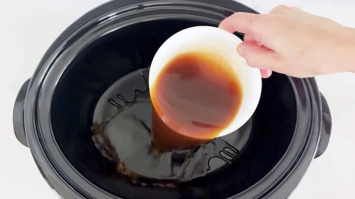 Pouring beef broth into the slow cooker.