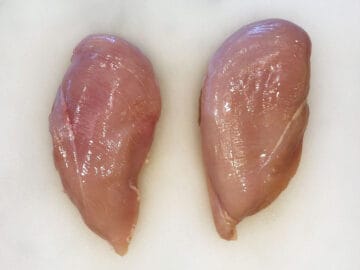 Two chicken breasts on a cutting board.