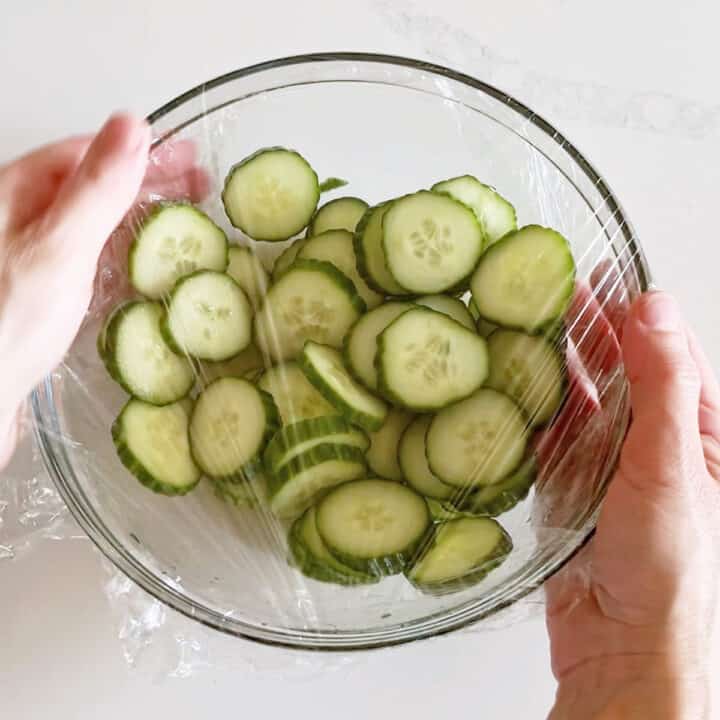 Covering the salad in cling wrap.