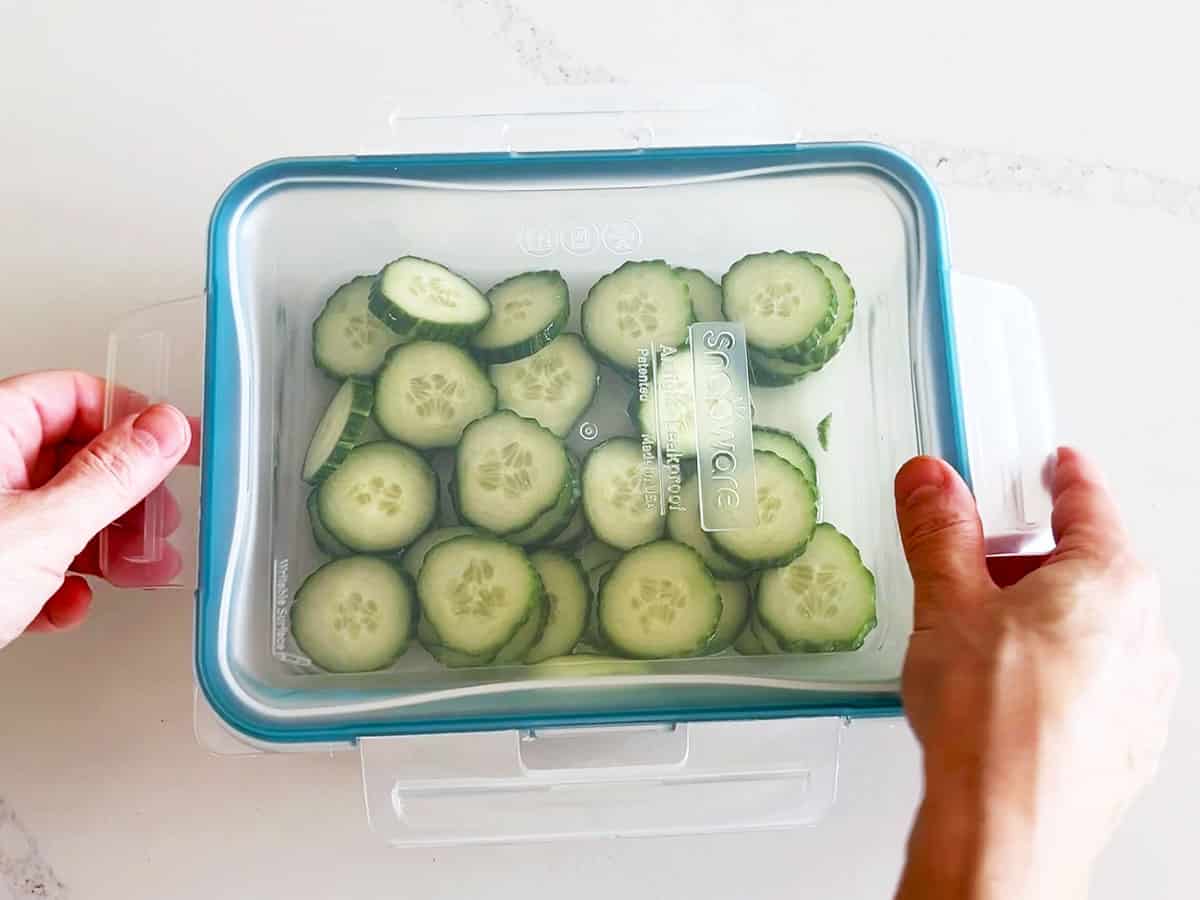 Storing cucumber vinegar salad in a glass food storage container.