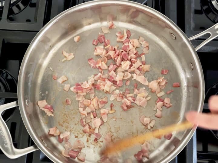 Cooking chopped bacon in a skillet.