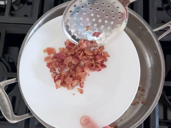 Transferring the cooked bacon to a plate.