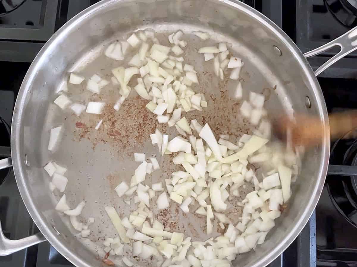 Cooking chopped onions in bacon grease.