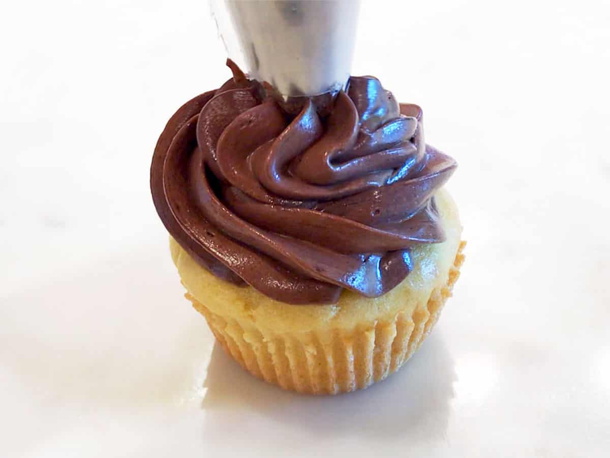 Piping the frosting on a cupcake.