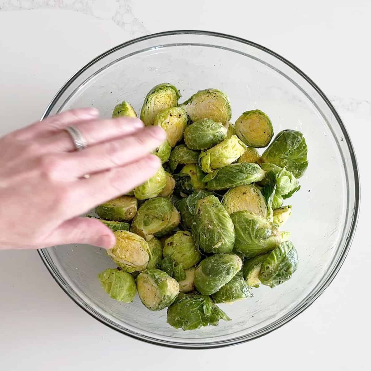 Coating Brussels sprouts in melted butter, honey, and spices.