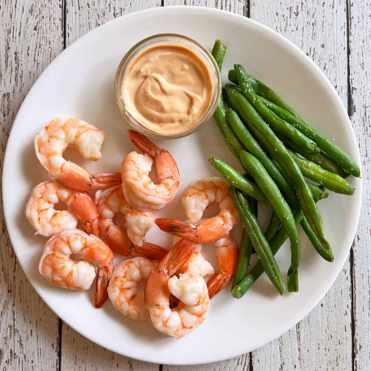 Boiled shrimp are served with sriracha mayo and green beans.