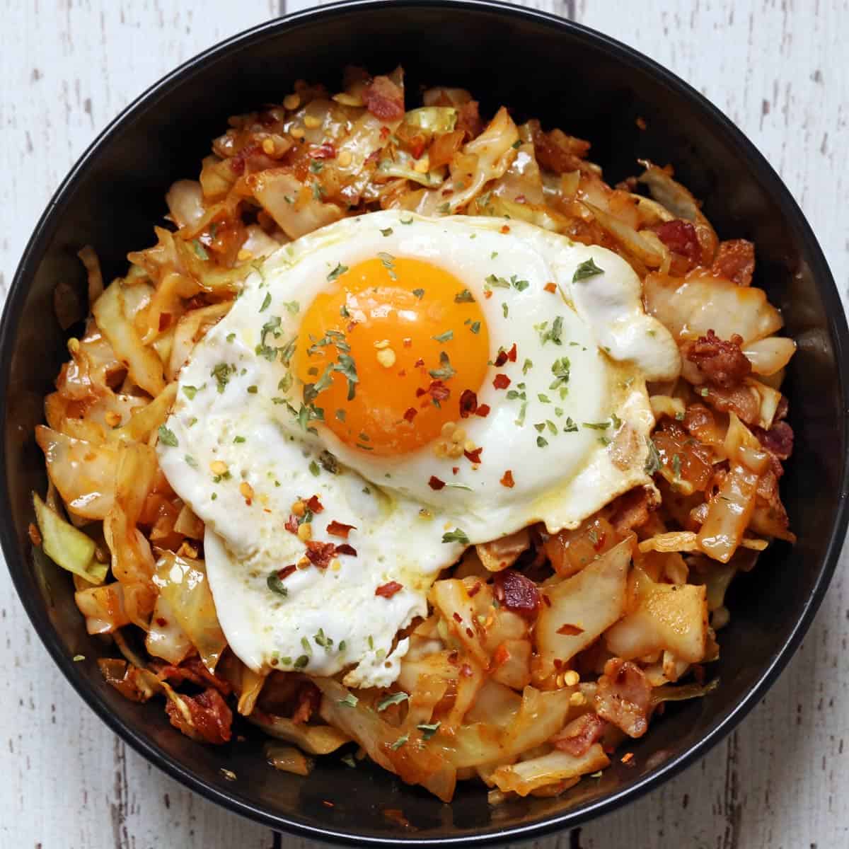 Leftover fried cabbage is topped with a fried egg.