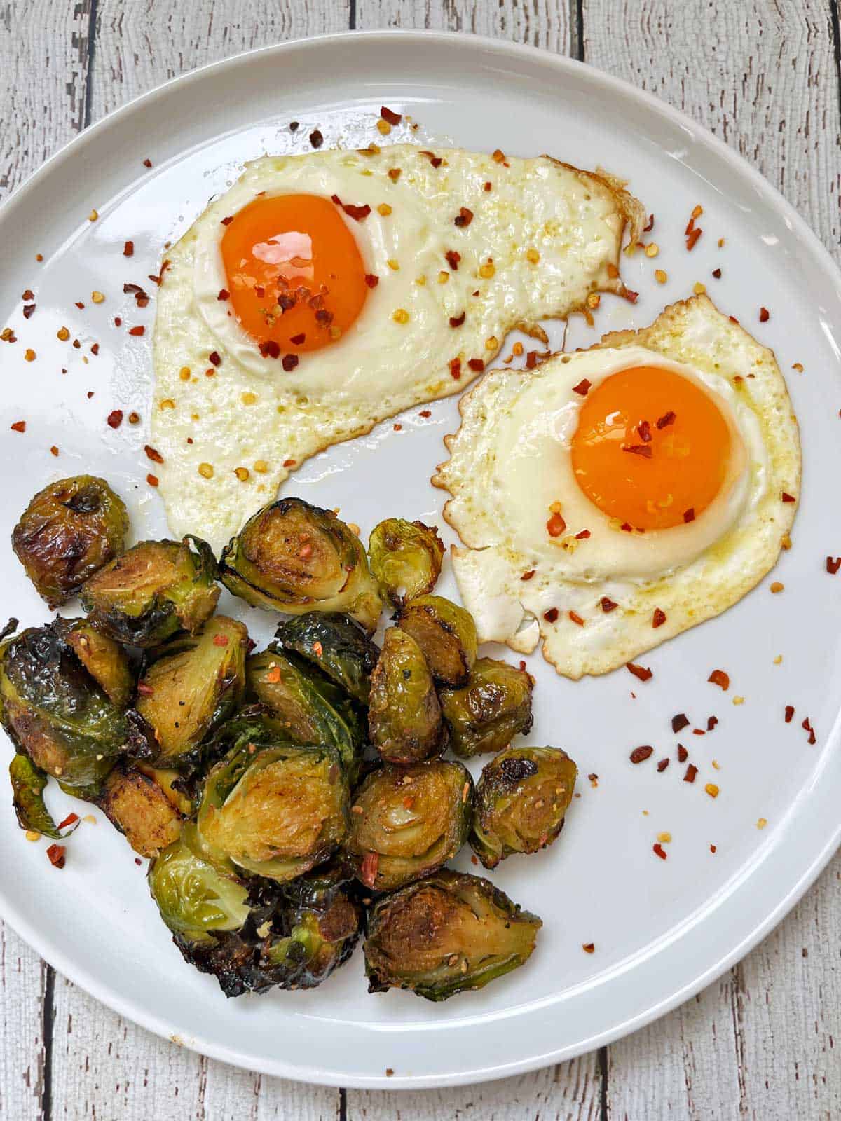 Roasted Brussels sprouts are served with fried eggs.