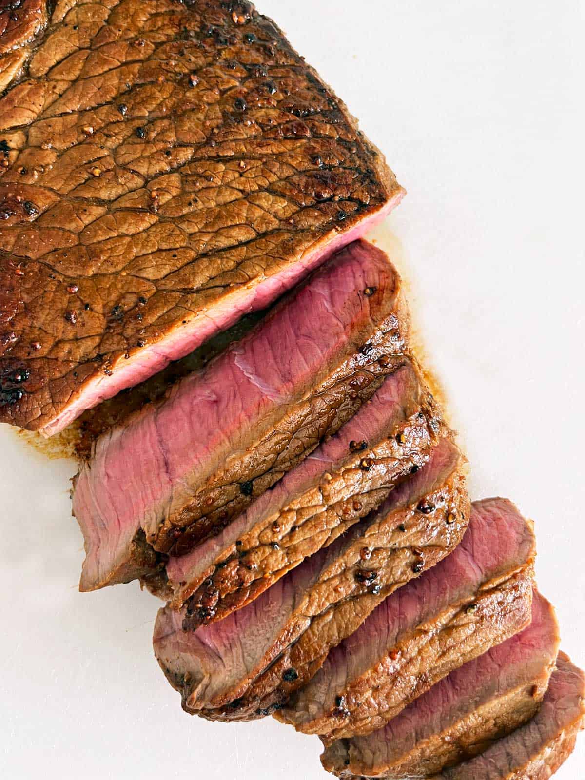 A sliced London broil steak on a cutting board.