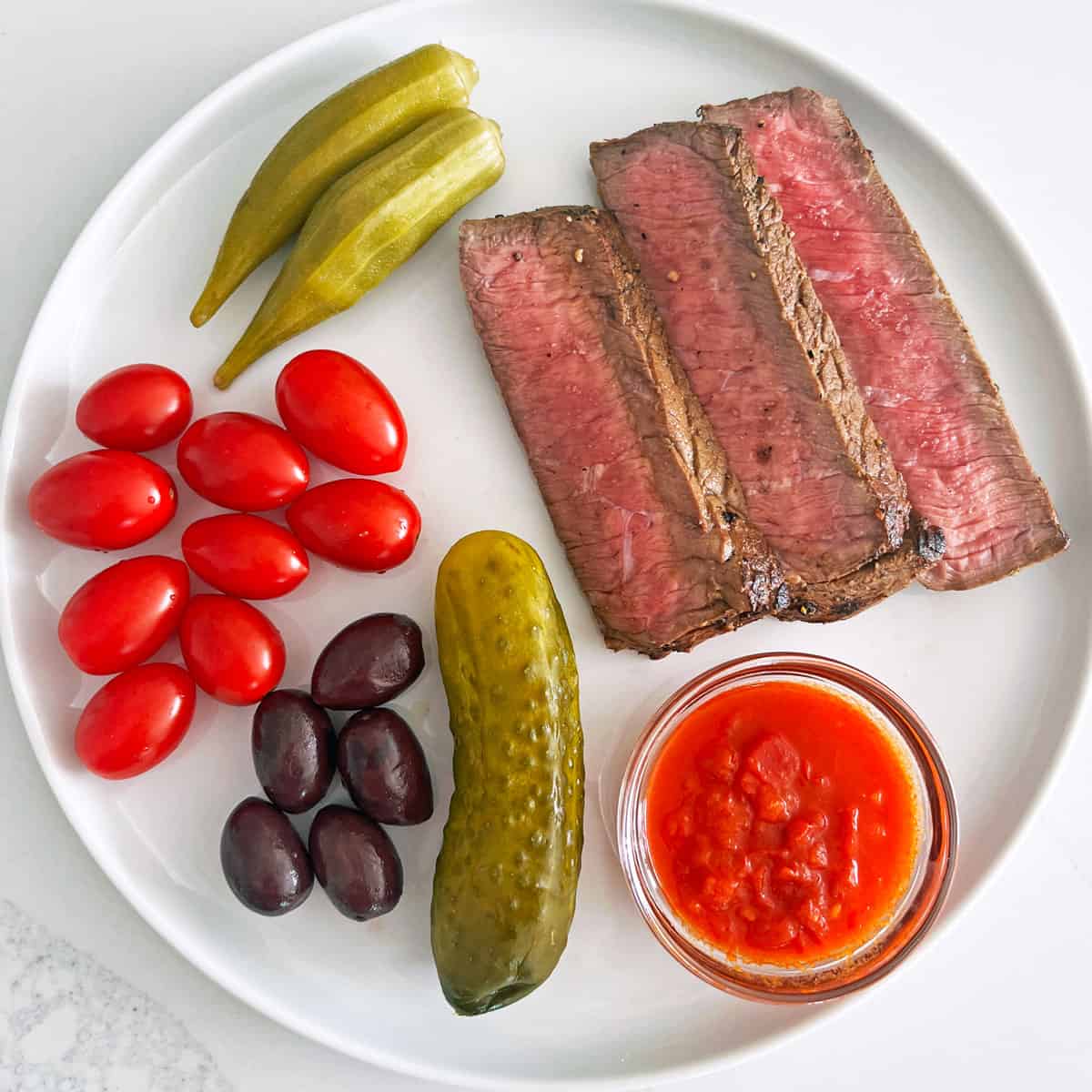 Leftover London broil served with tomatoes and pickles.