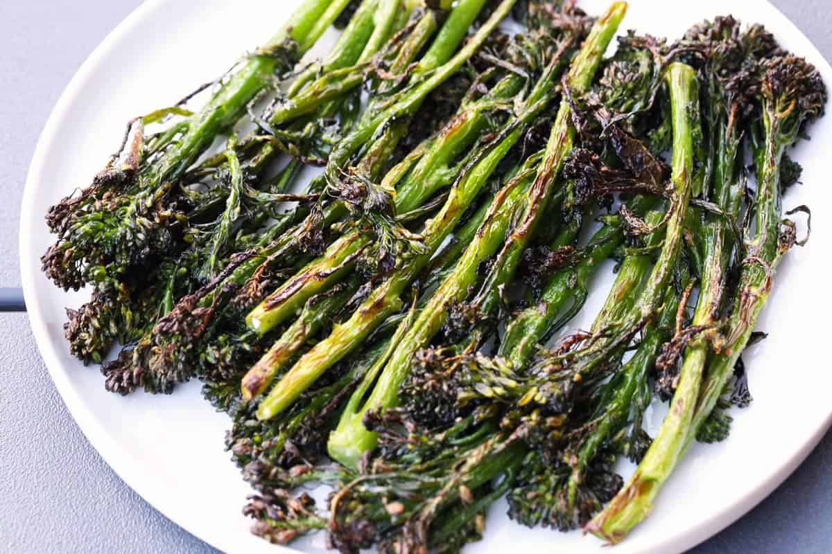 Roasted broccolini is served on a white plate.