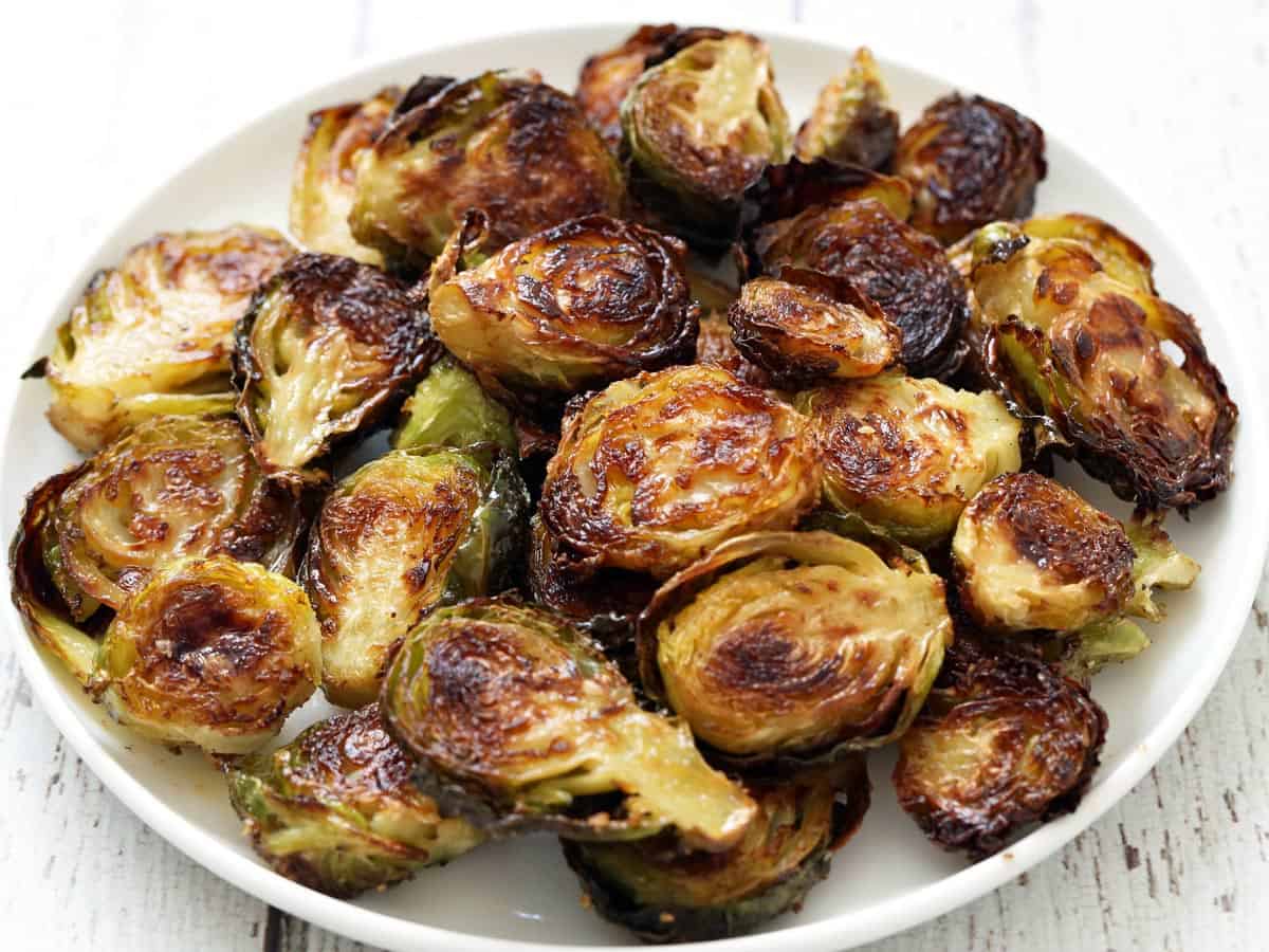 Roasted Brussels sprouts are served on a white plate.