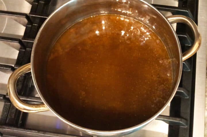 Short ribs cooking liquids in a saucepan.