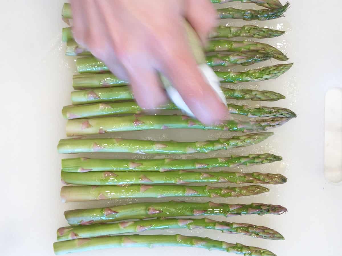 Spraying the asparagus with oil.