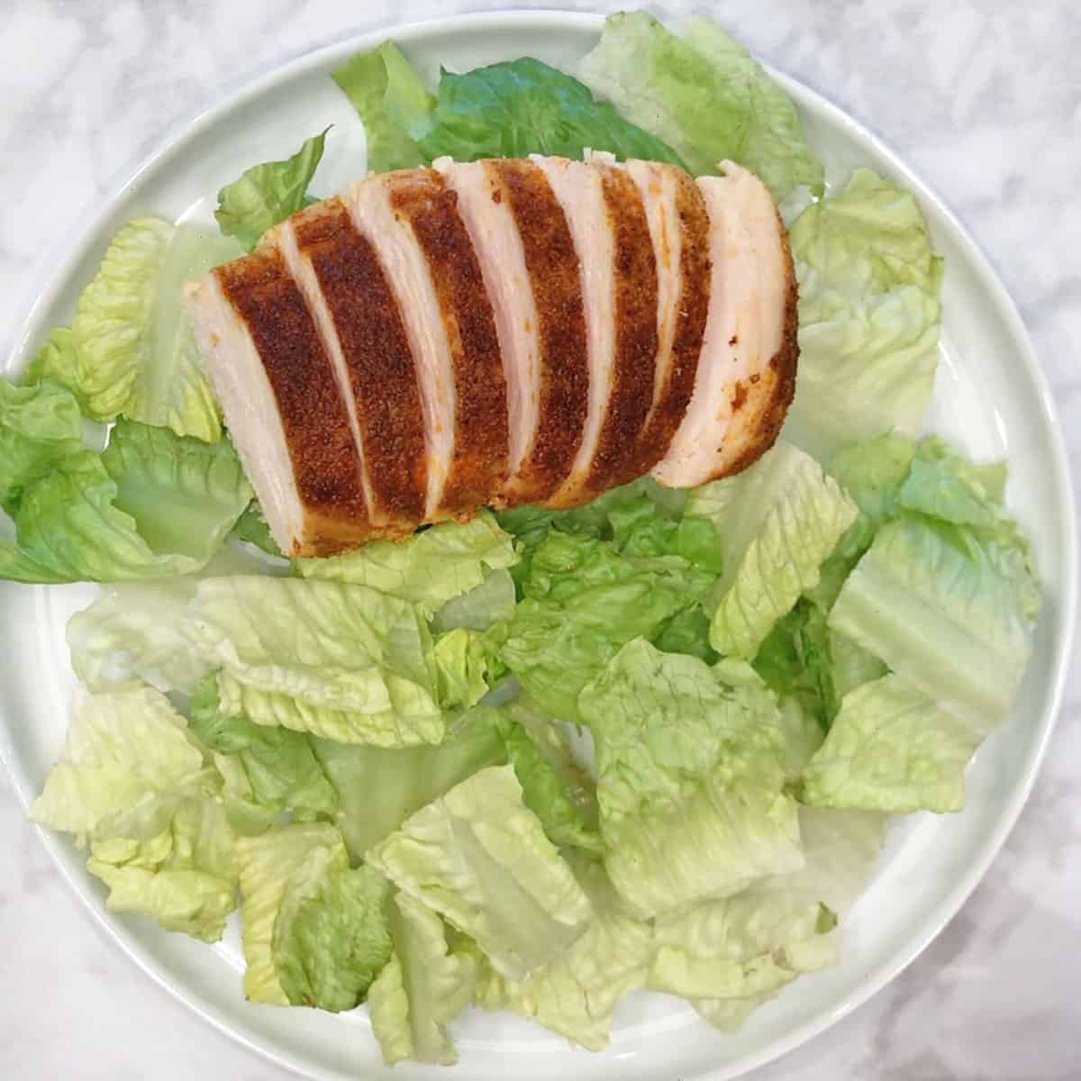 A plate with lettuce and sliced chicken.