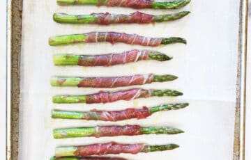 Arranging the wrapped asparagus on a baking sheet.