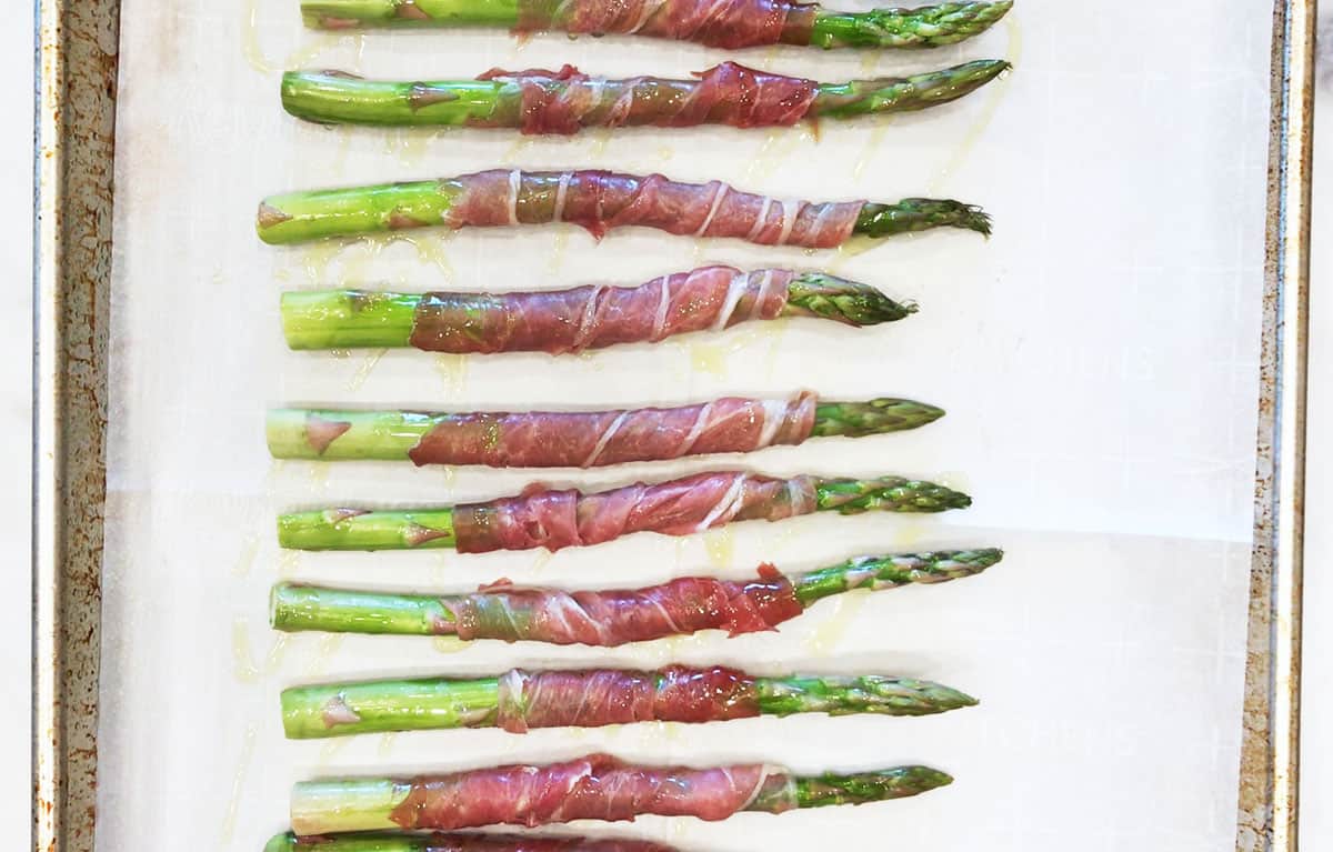 Arranging the wrapped asparagus on a baking sheet.