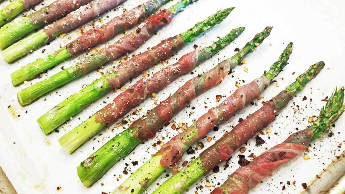 The prosciutto-wrapped asparagus is ready on the baking sheet.