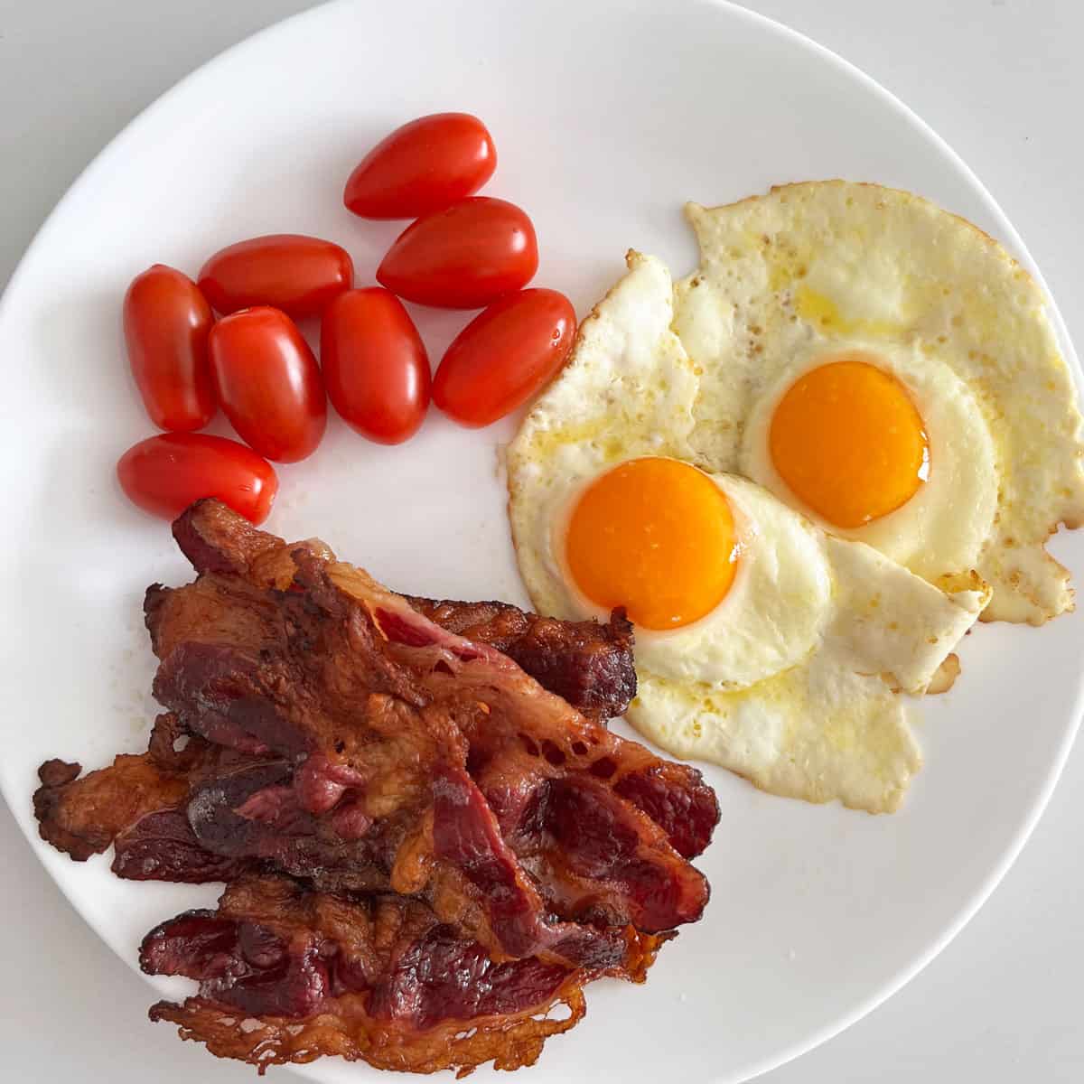 Beef bacon served with eggs and tomatoes.
