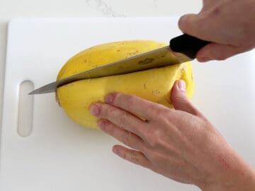 Cutting the spaghetti squash with a sharp knife.