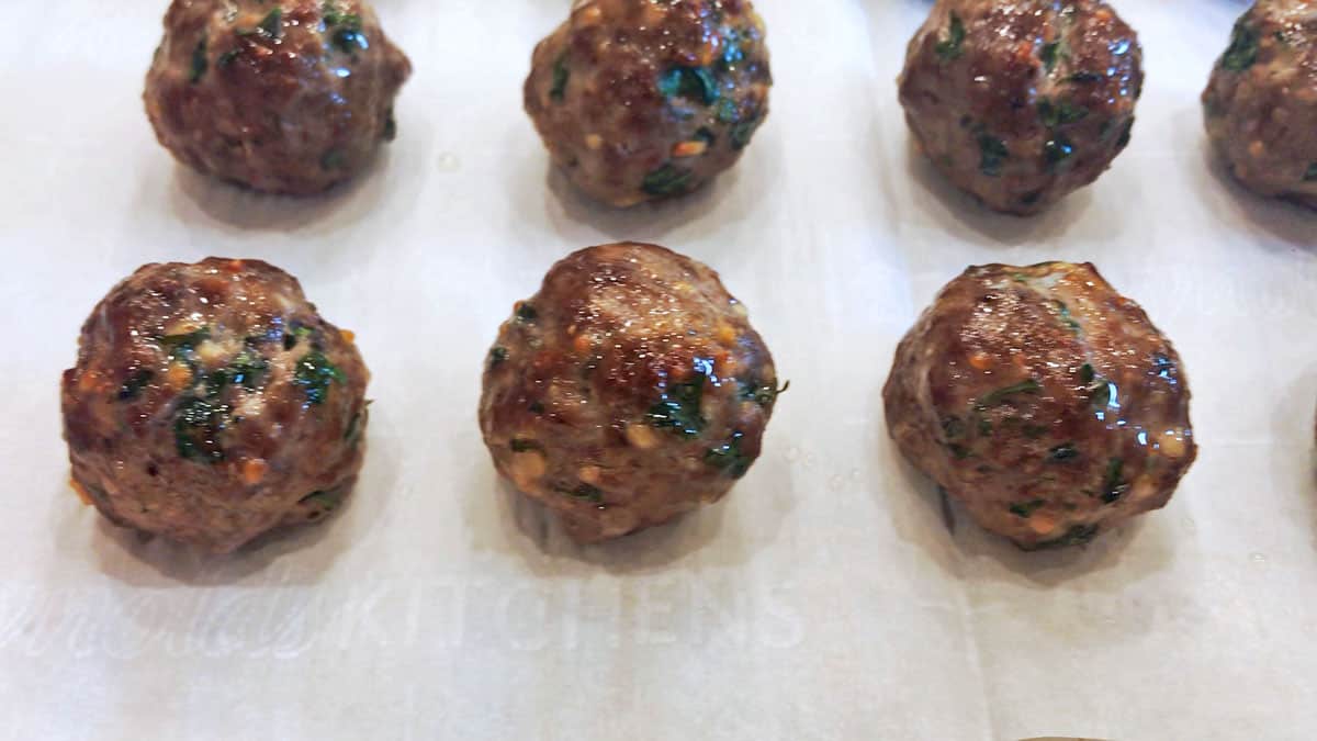The meatballs are fully baked on the pan.