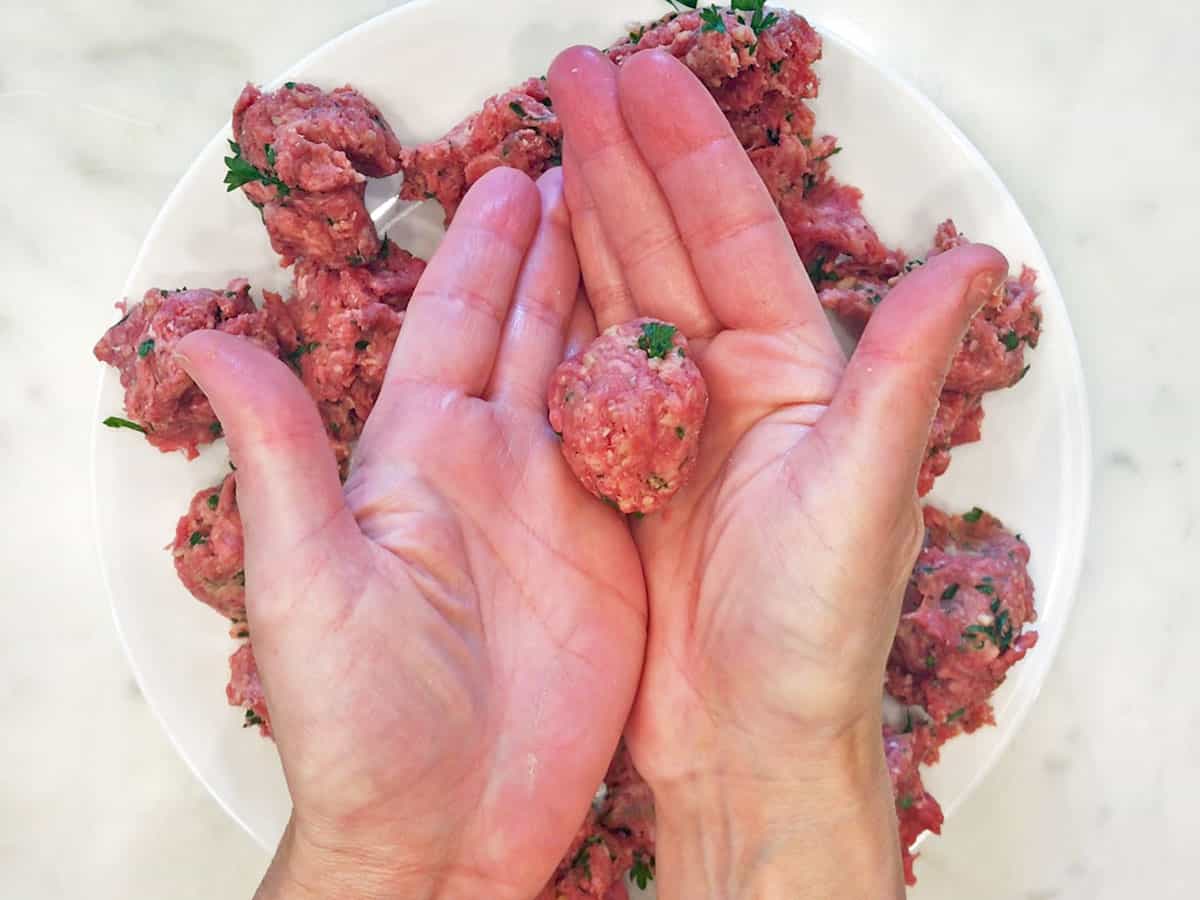 Shaping the meat portions into meatballs.