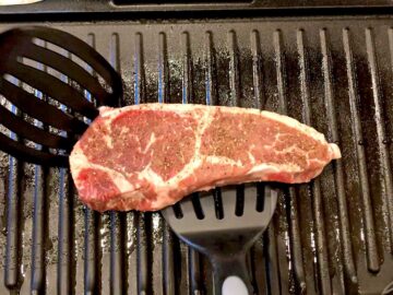 Placing a steak on the grill.