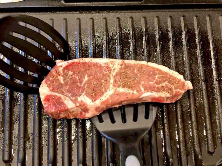 Placing a steak on the grill.