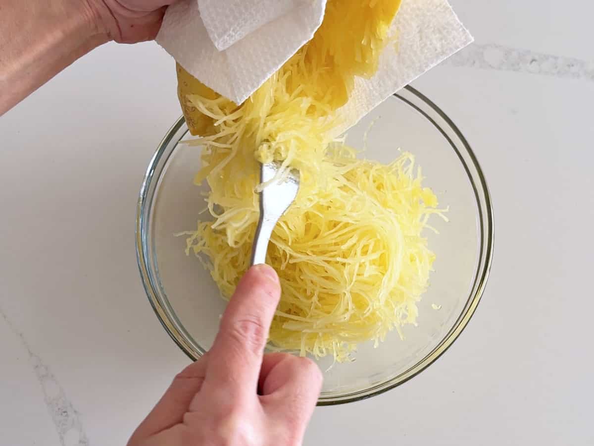 Transferring the spaghetti squash strands to a bowl.